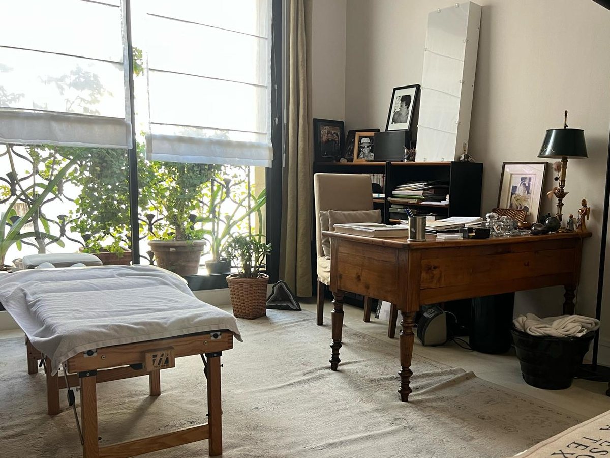 Le cabinet de Nathalie Abondance : table de soin, bureau ancien et grandes fenêtres sur la verdure